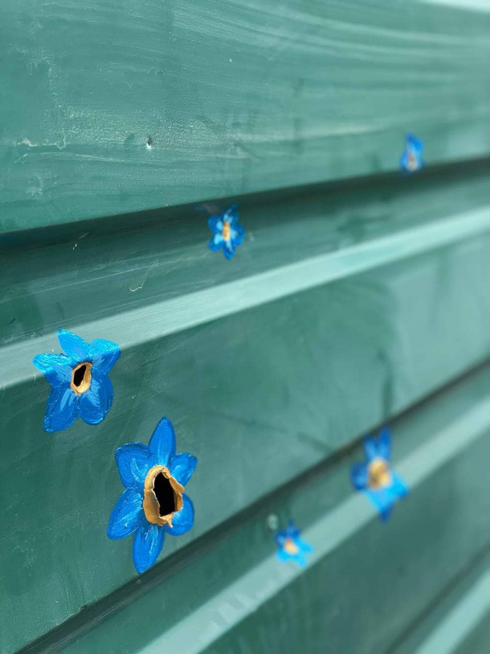 В Буче художница "превратила" отверстия от пуль в цветы (фото)